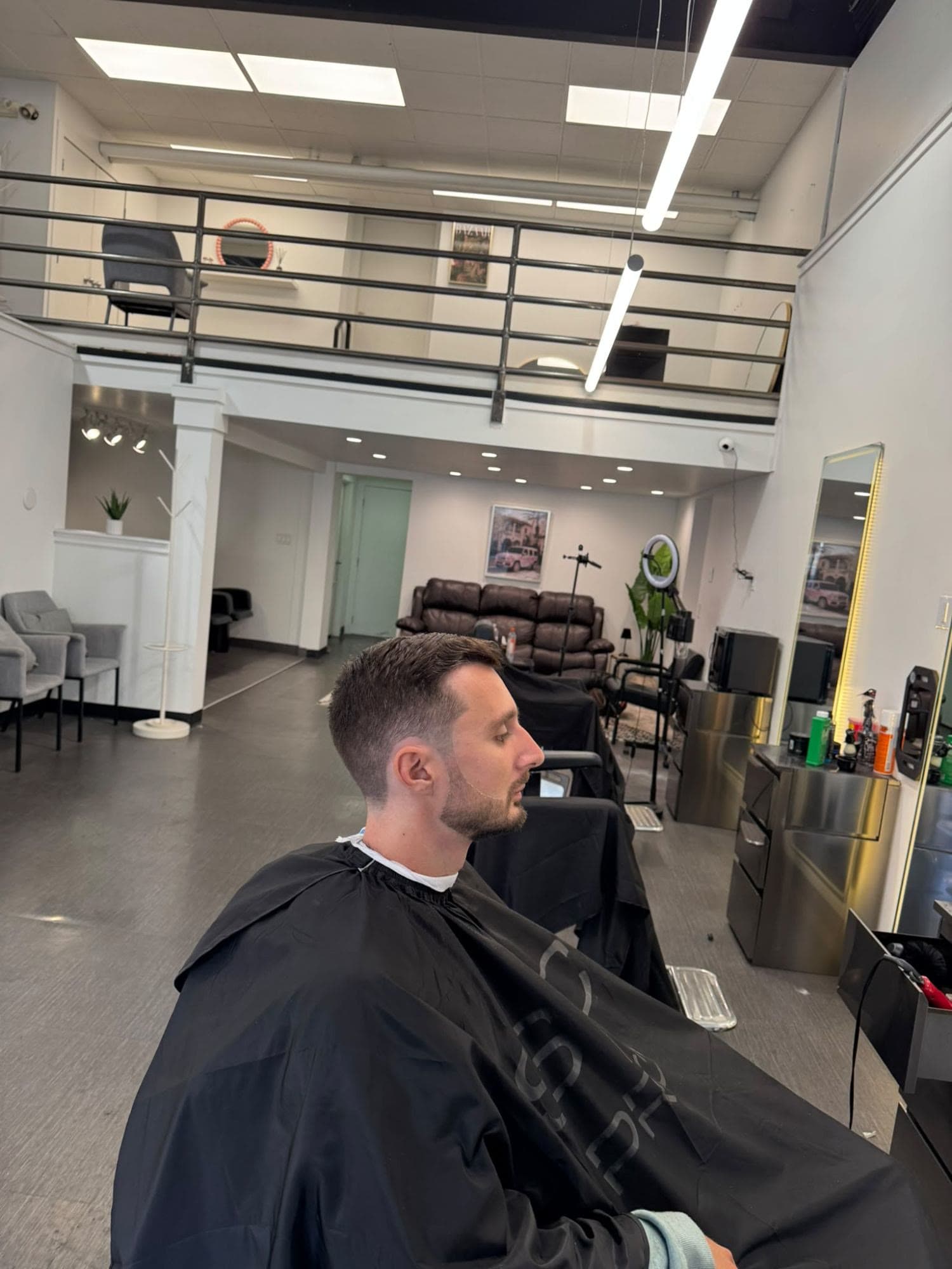 Client with a fresh short taper in the chair, the Glasscut floor and mezzanine behind him