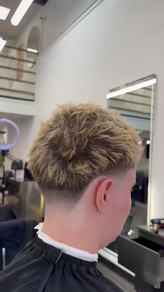 Blond textured cut with a taper fade, seen in the Glasscut mirrors