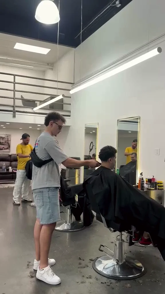 A Glasscut barber cutting a client's hair on the shop floor on Douglas St